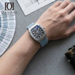 Wrist shot of Richard Mille RM 67 01 fitted with blue denim watch strap by Daydaywatchband, lifestyle POV with Pantone color fan and camera on grey concrete background