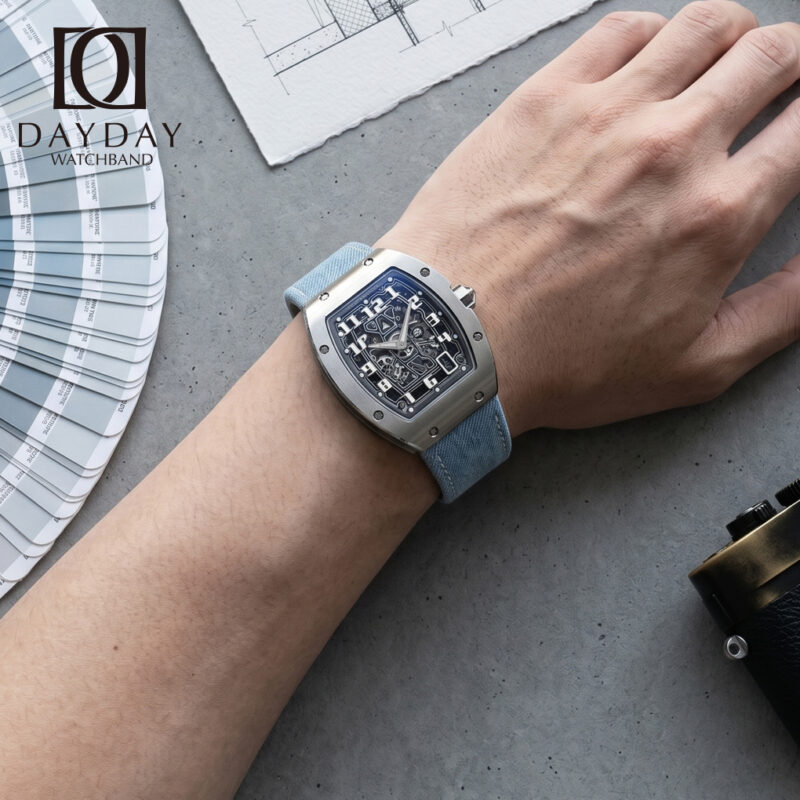 Wrist shot of Richard Mille RM 67 01 fitted with blue denim watch strap by Daydaywatchband, lifestyle POV with Pantone color fan and camera on grey concrete background