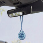 Light blue neck strap for AP Swatch Royal Pop hanging from car rearview mirror — leather lanyard for Swatch AP Royal Pop used as stylish car accessory display