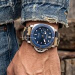 a handmade canvas strap for Panerai Submersible bronze case, camouflage pattern, seated in a vintage sports car