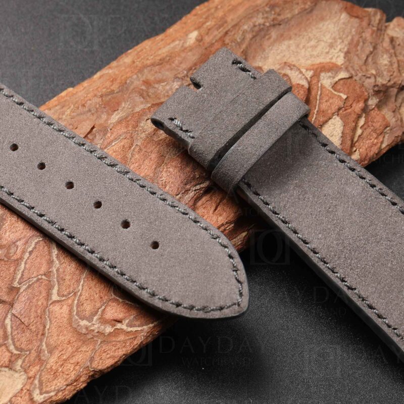 Grey nubuck strap for Vacheron Constantin Overseas displayed on warm tan leather background
