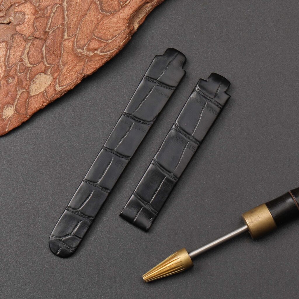 Side profile view of custom alligator watch band for Ebel Beluga Tonneau Mini on dark background, with artisan burnishing tool